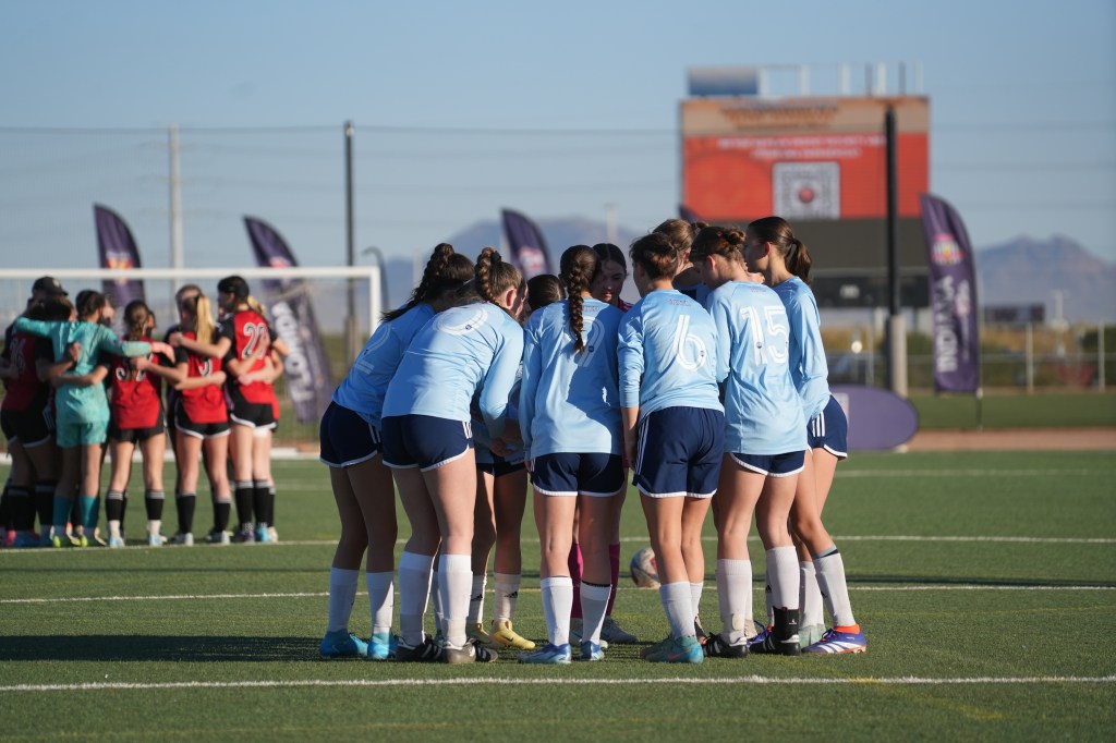 Players gathered on a soccer field. News Article: Age Group Formation